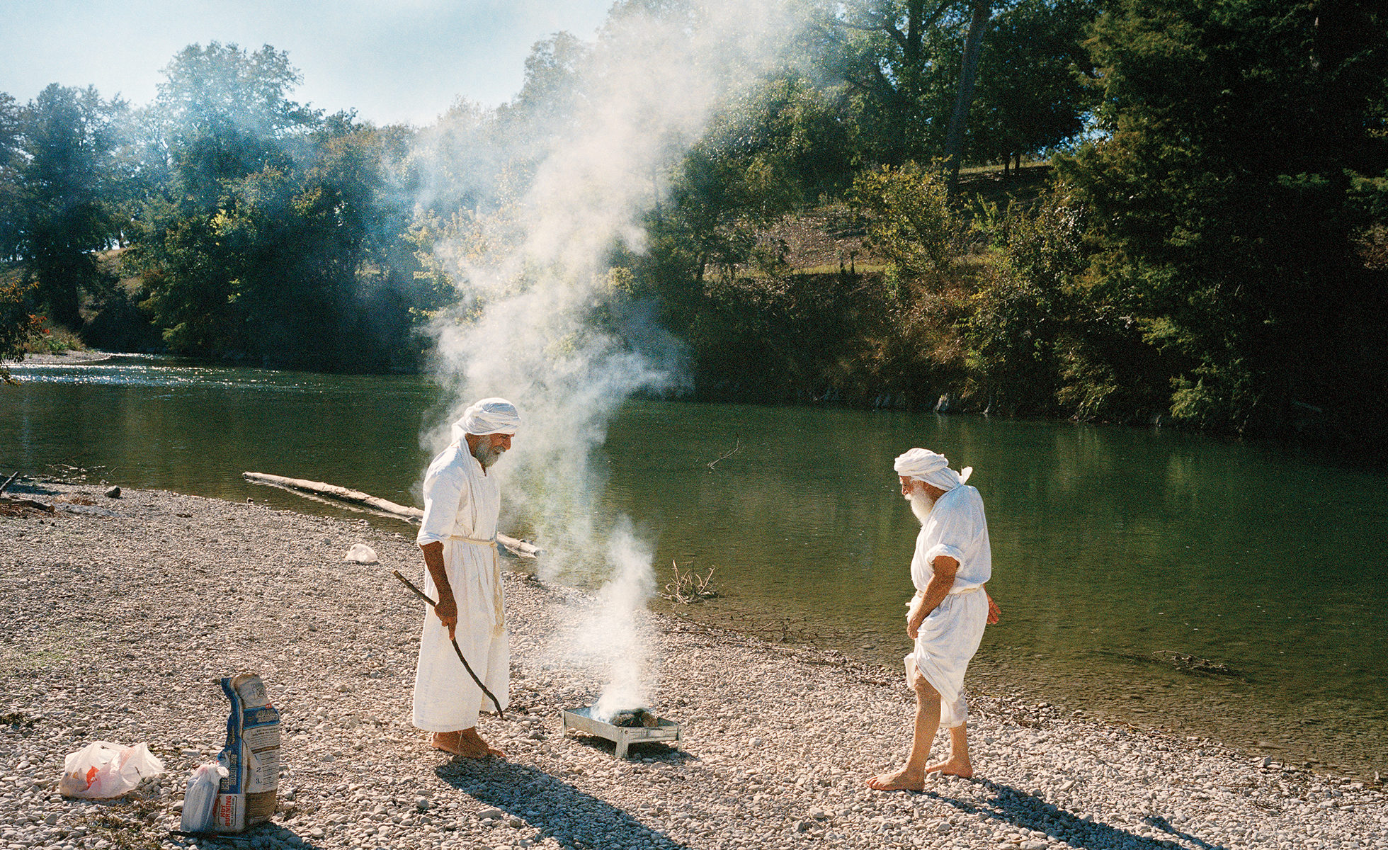 Shahram Ebadfardzadeh, left, and Hormoz Ebadeh Ahvazi prepare a fire during a day of remembrance at the Guadalupe River near San Antonio. They'll eat while praying for the souls of people who have died.