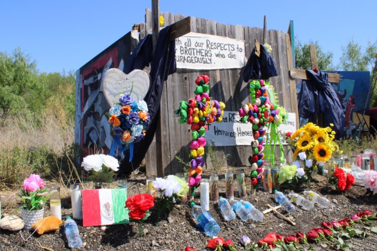 Flowers, candles, crosses and signs are gathered at the memorial site for immigrants who died in a truck near San Antonio. One sign reads, "With all our respects to our brothers who die courageously"."