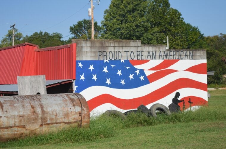 An American flag mural painted on the side of a metal building in rural Arkansas.