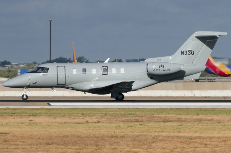 A private jet with a custom gray paint job and the Gothams LLC logo on the side, resting on the runway.